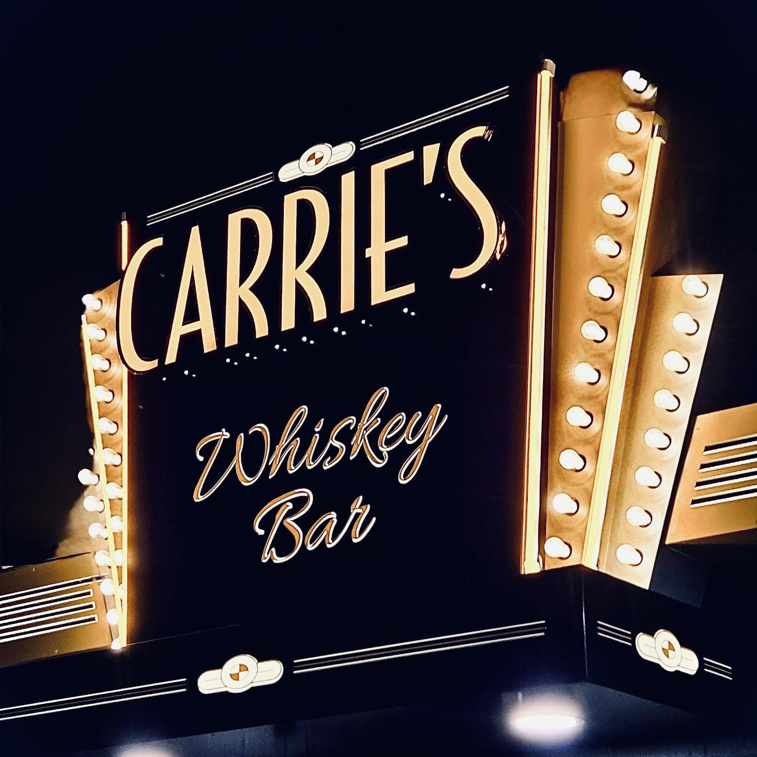 The lit marquee sign reading Carrie’s Whiskey Bar