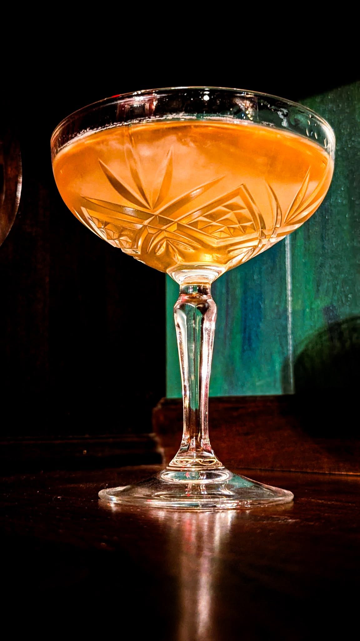A cut-crystal coupe on the bar in front of a green light