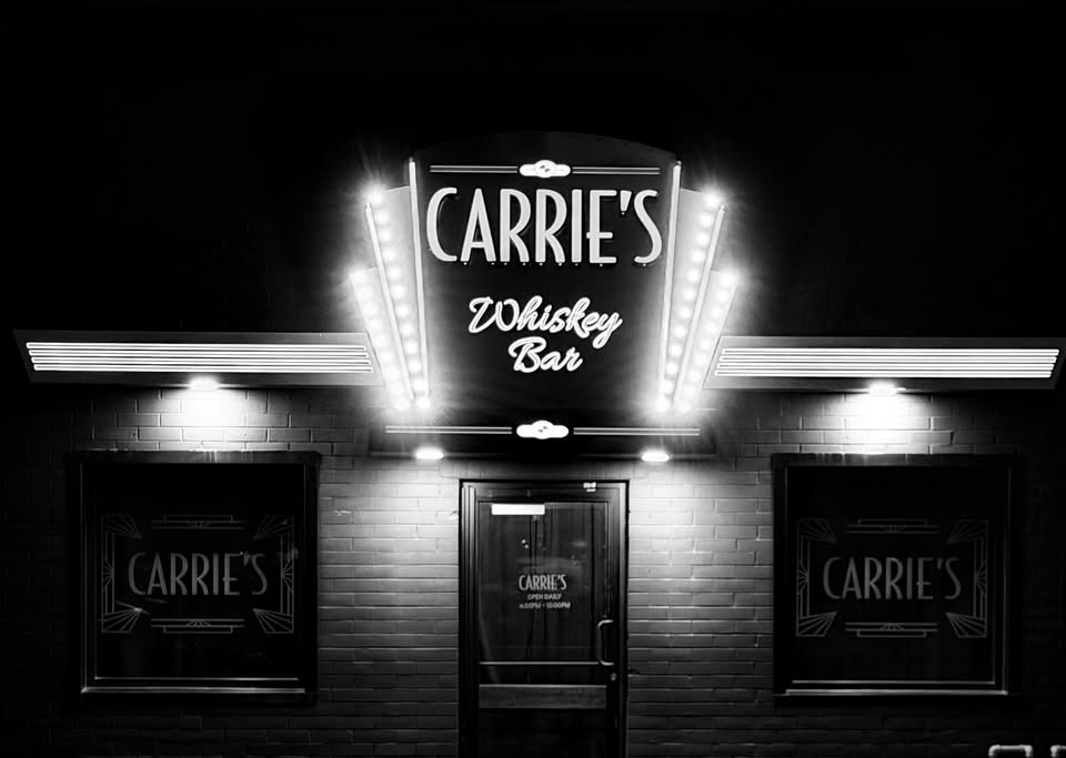 The Carrie’s storefront at night, marquee lit, in black and white