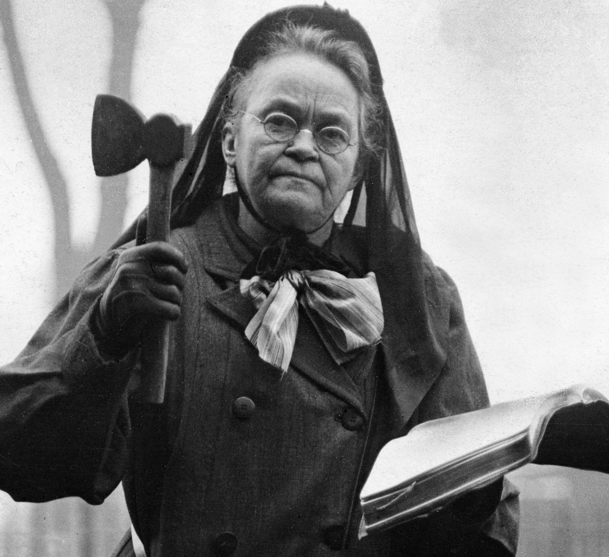 Carrie Nation holding a hatchet and an open Bible